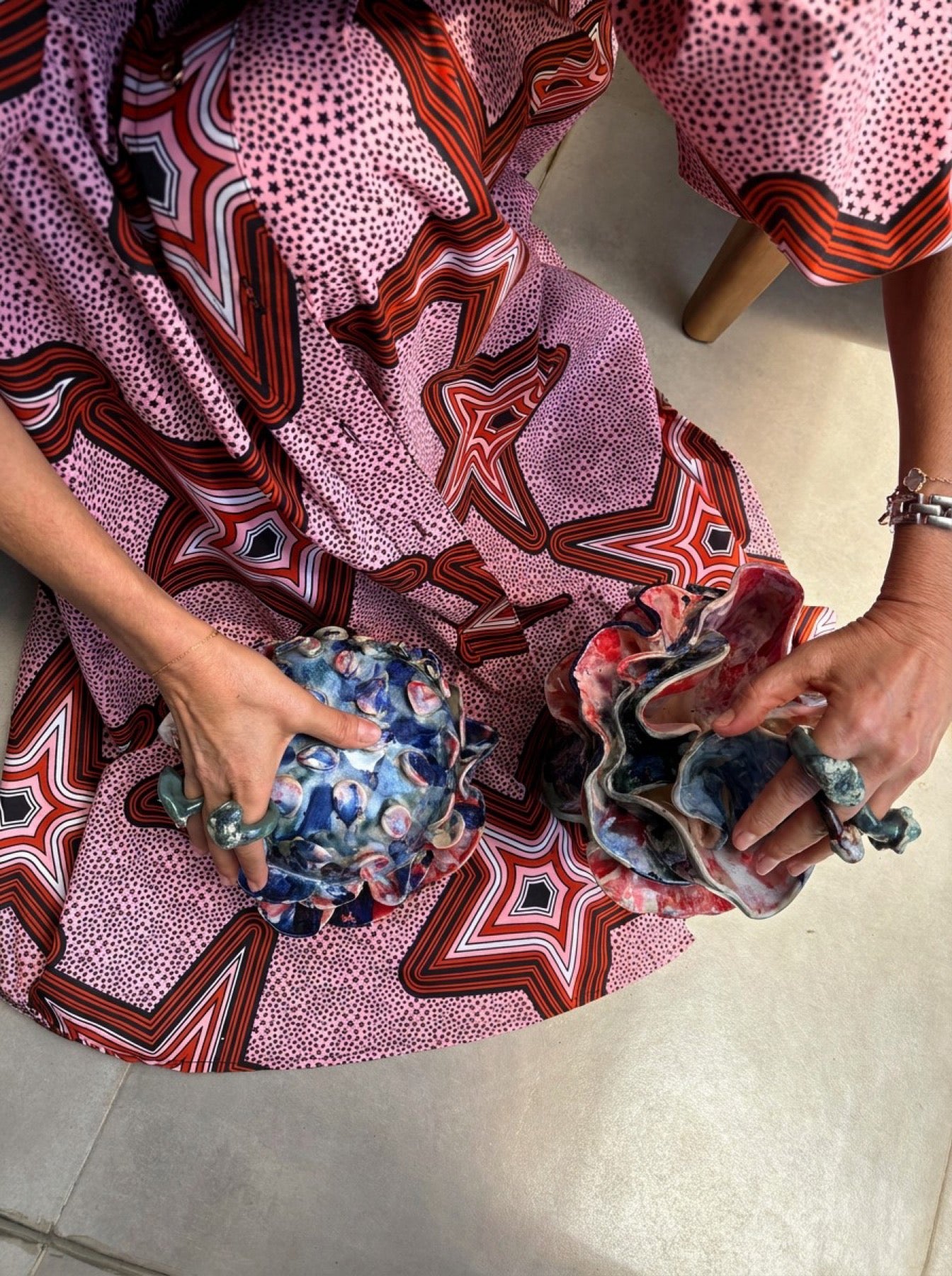 Duas peças em cerâmica seguras sobre um vestido estampado
