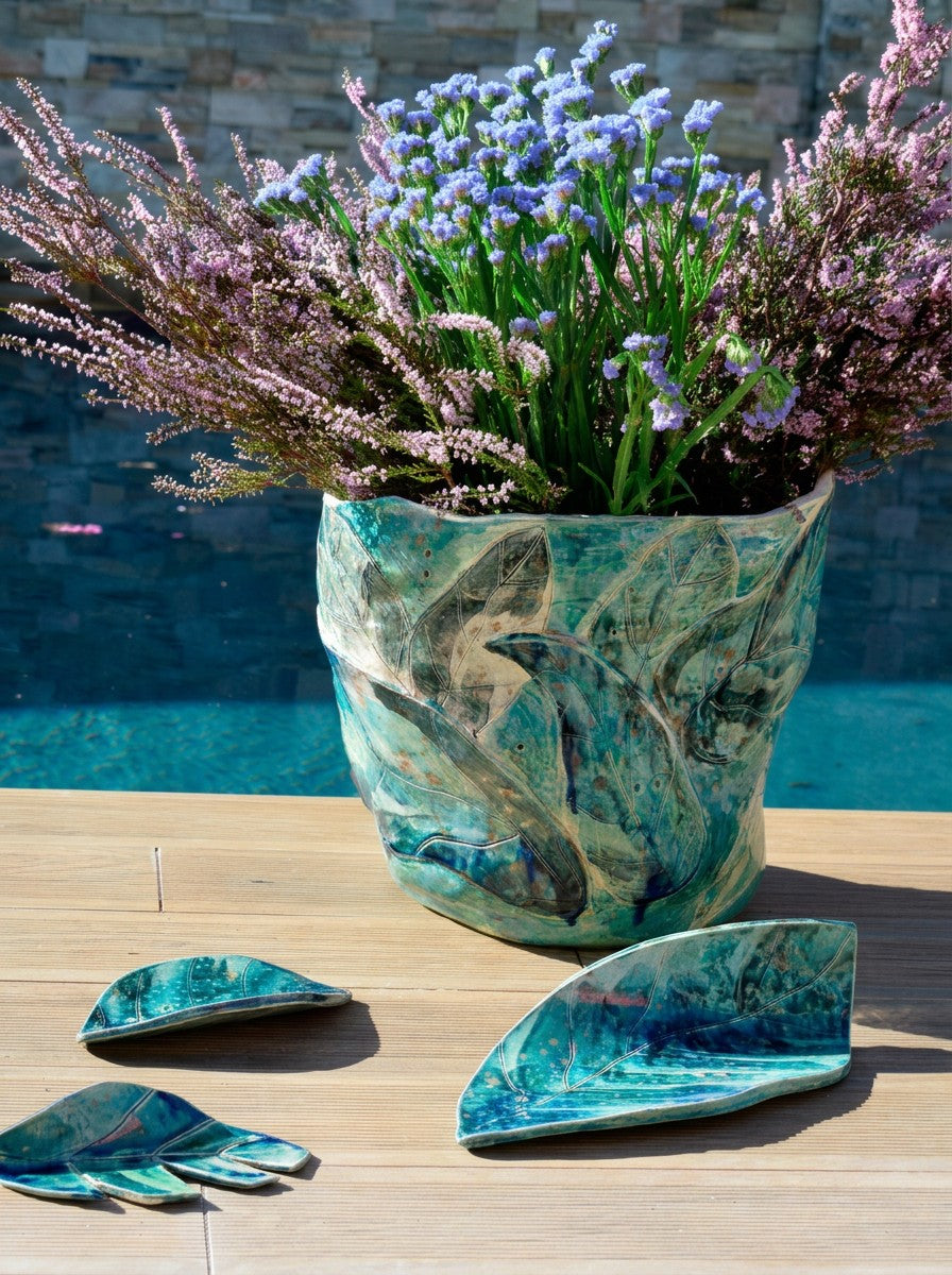 Vaso de folhas com flores junto à piscina